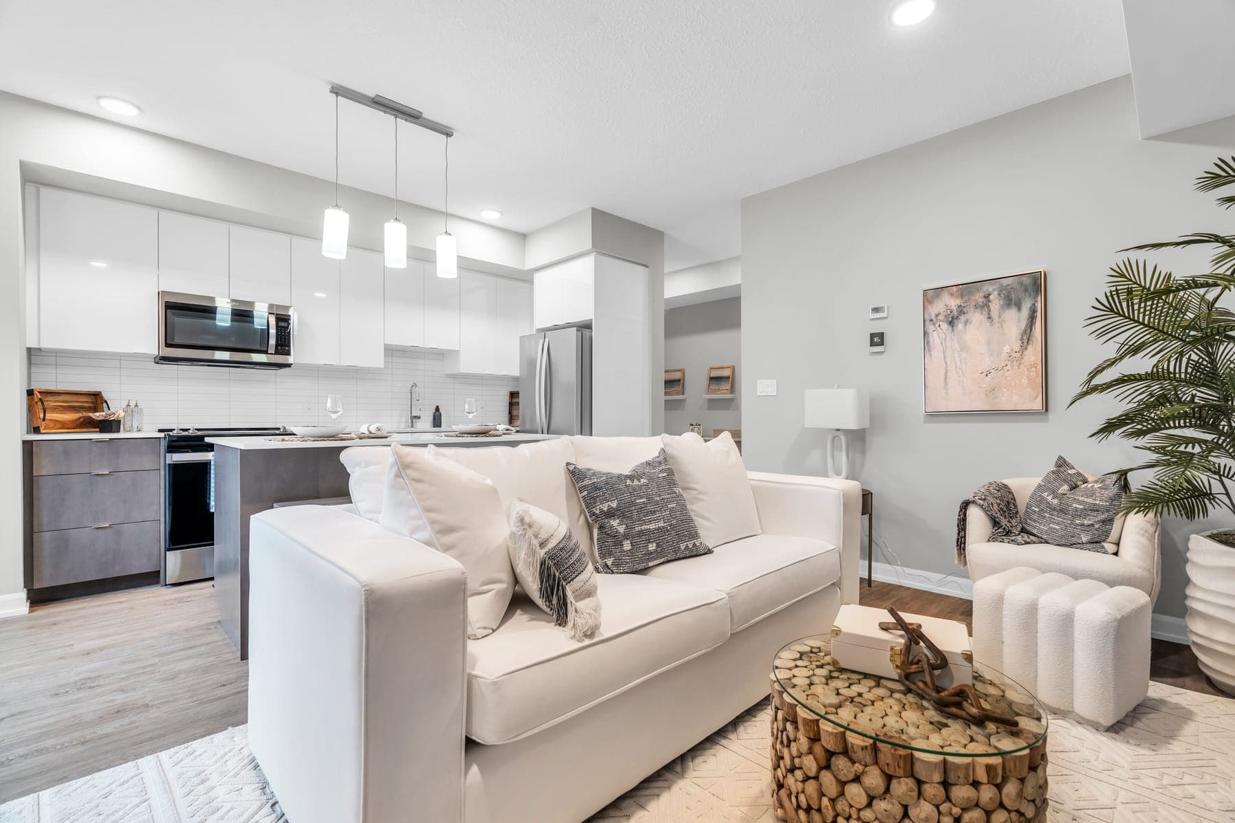 Living room and kitchen of the Monarch model home: white cabinets, an island and wide-plank floors.