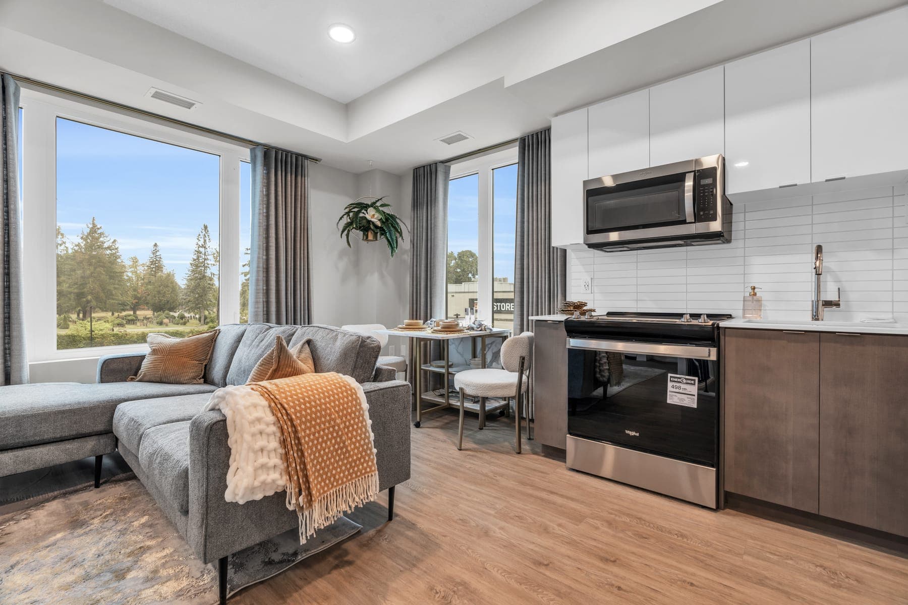 Bright living room and kitchen of the Sapphire model home with a tall window.